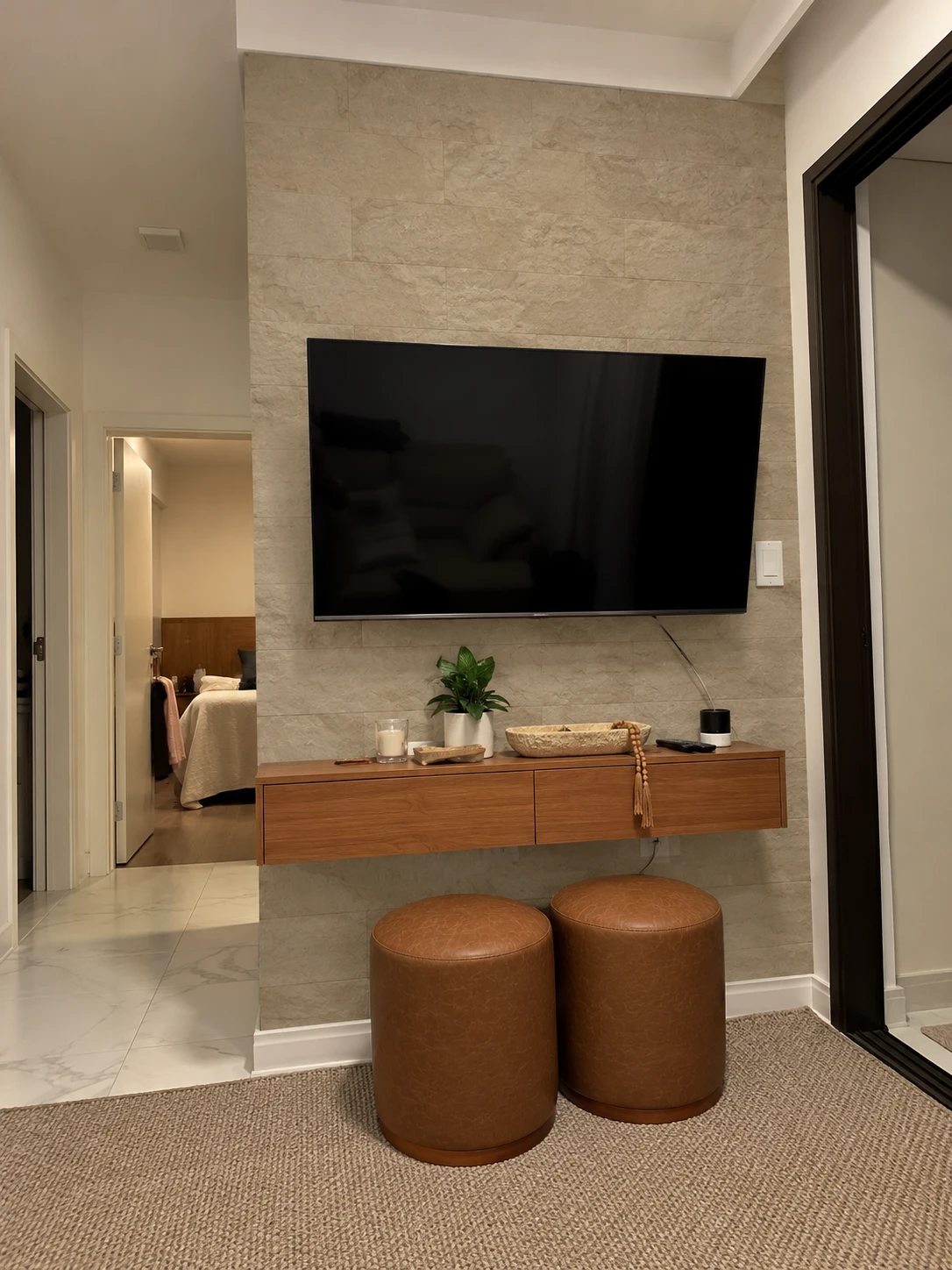Painel de TV revestido com Rockface em tom areia, com aparador de madeira suspenso